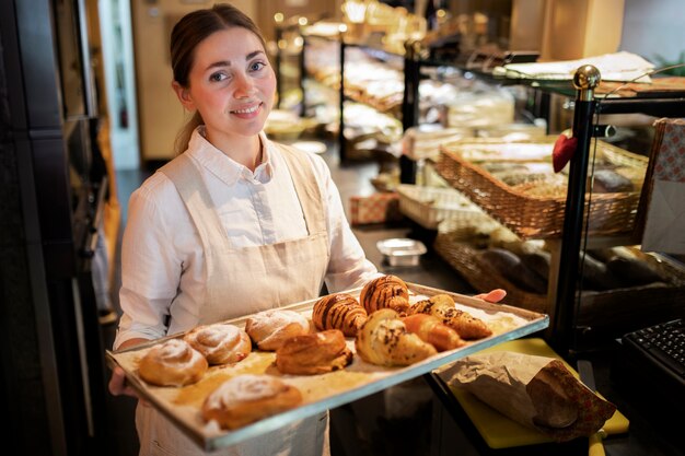 Medium shot smiley woman holding tray