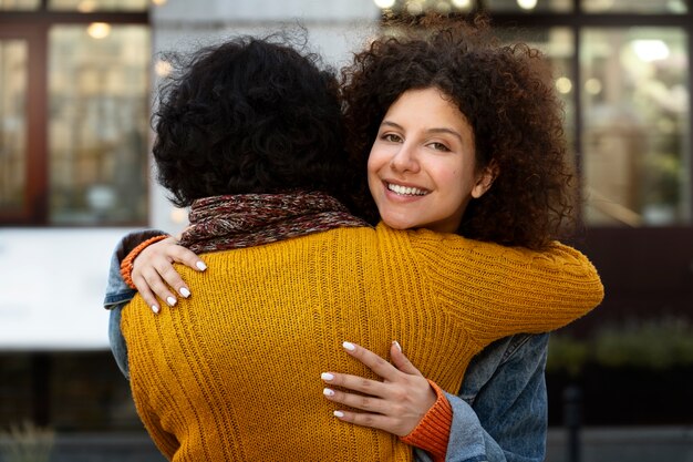 Medium shot smiley woman hugging friend