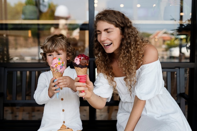 중간 샷 웃는 여자와 아이스크림을 든 아이