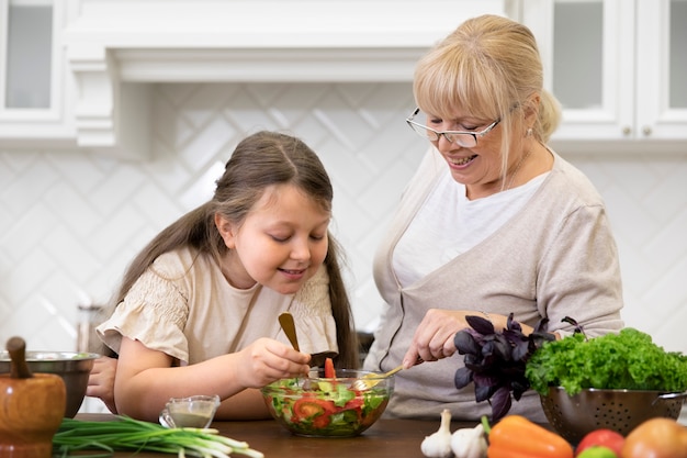 Medium shot smiley woman and kid with salad