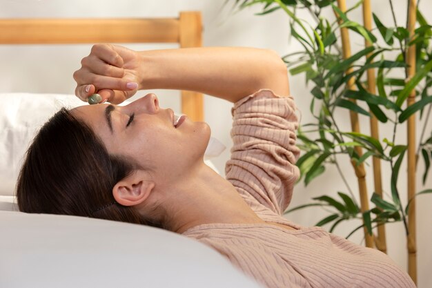 Medium shot smiley woman laying in bed with crystal