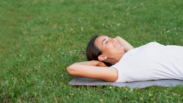 Medium shot smiley woman laying on grass