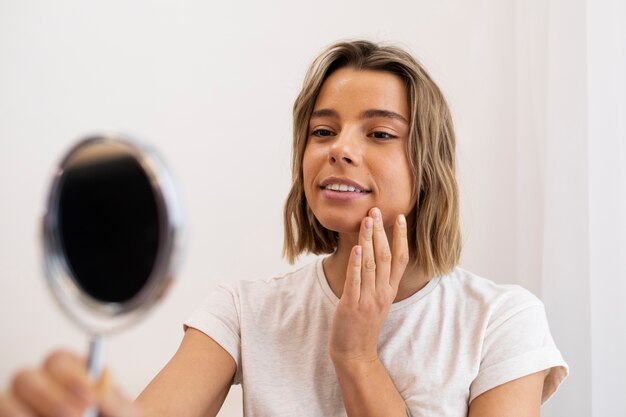 Medium shot smiley woman looking in the mirror