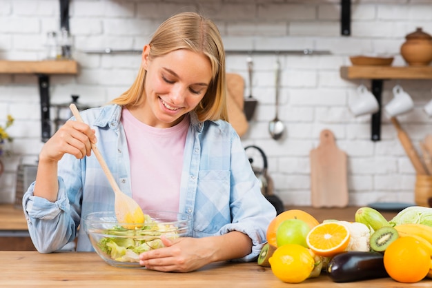 Donna di smiley del colpo medio che produce alimento sano