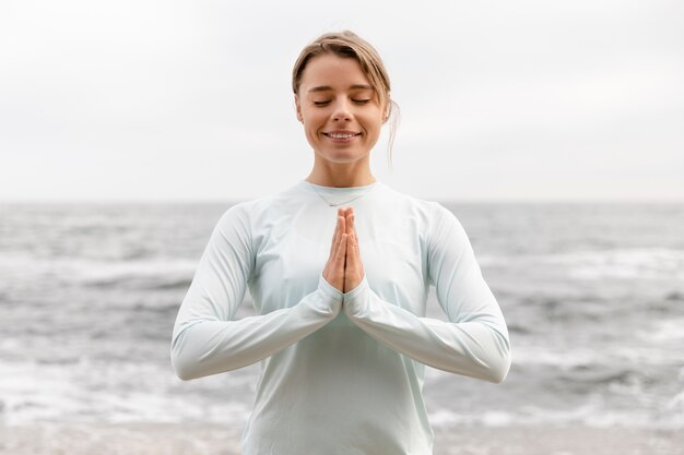 Medium shot smiley woman meditating