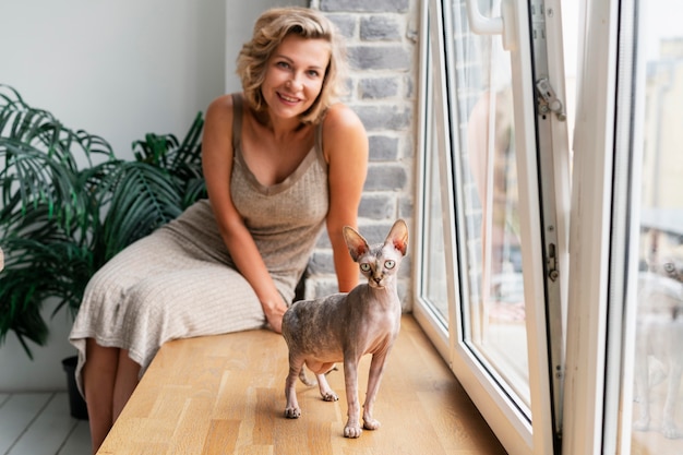 Medium shot smiley woman playing with cat