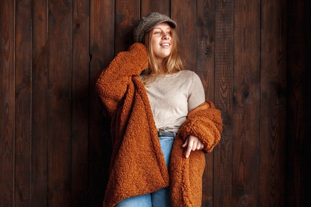 Medium shot smiley woman posing with wooden background