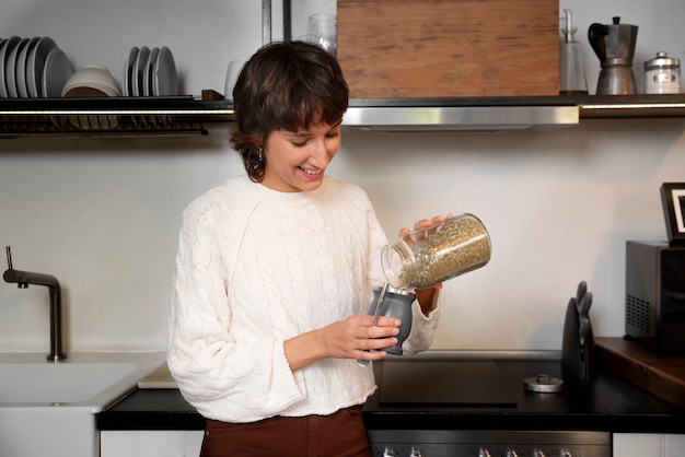 ミディアムショットのスマイリー女性が飲み物を注ぐ