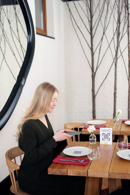 Free photo medium shot smiley woman scanning qr at restaurant