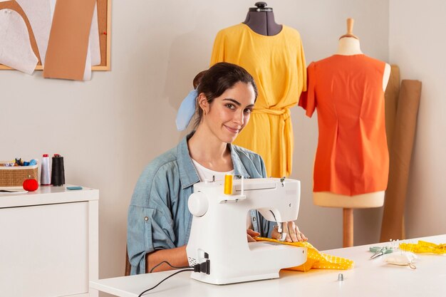 Medium shot smiley woman  sewing with machine