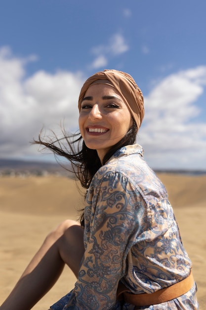 Foto gratuita donna sorridente del colpo medio che si siede sulla sabbia