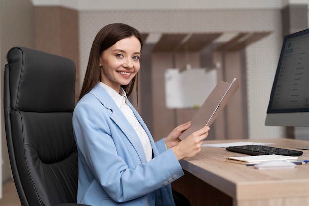 Foto gratuita donna sorridente del colpo medio che si siede al lavoro