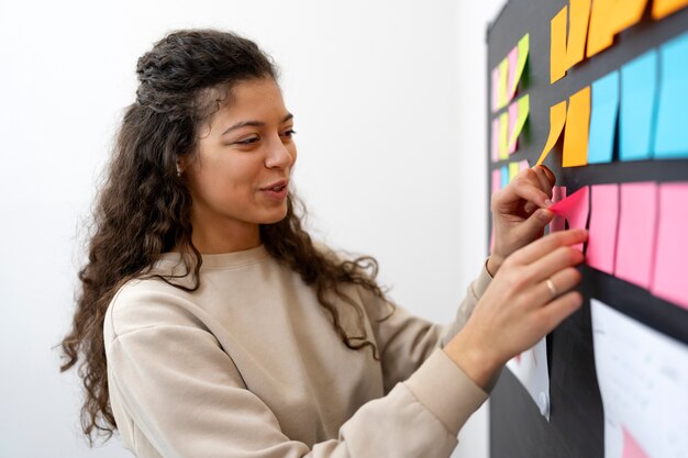 Medium shot smiley woman sticking post it