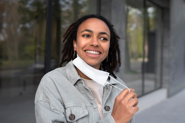 Medium shot smiley woman taking mask off outdoors