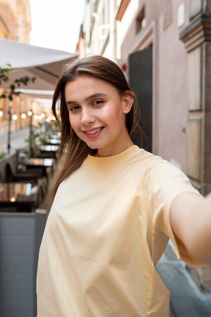 Medium shot smiley woman taking selfie outdoors