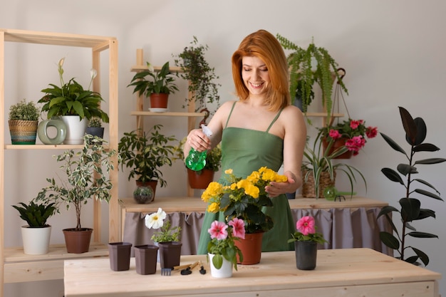 Medium shot smiley woman watering flower