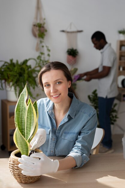 家に植物を持った中型の笑顔の女性