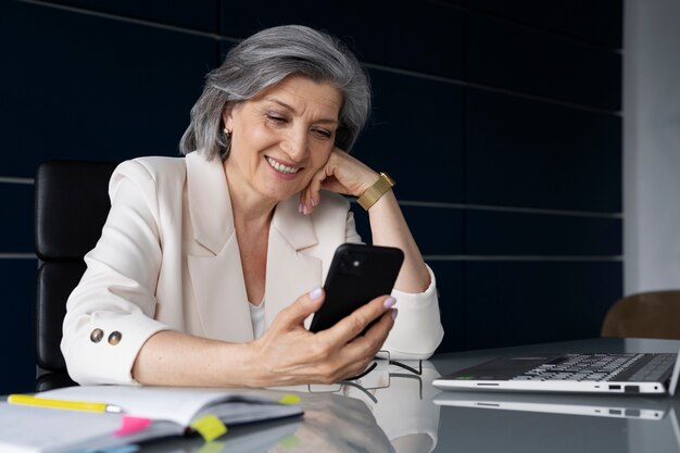 Medium shot smiley woman with smartphone