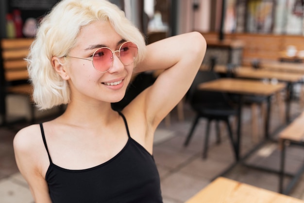 Foto gratuita donna sorridente a colpo medio con occhiali da sole