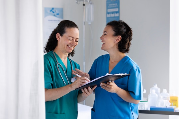 Donne sorridenti del colpo medio che chiacchierano al lavoro