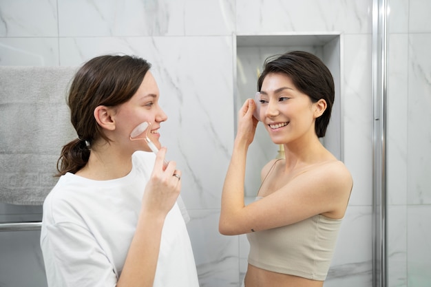 Medium shot smiley women holding gua sha tools