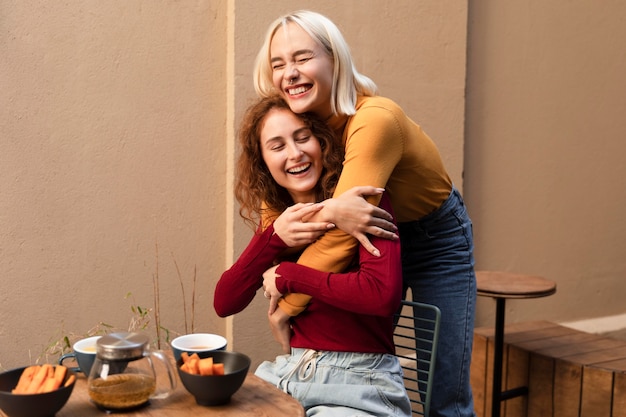 Medium shot smiley women hugging