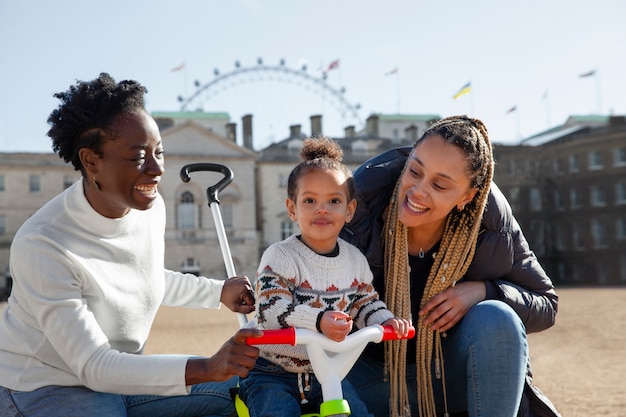 Medium shot smiley women and kid with tricycle