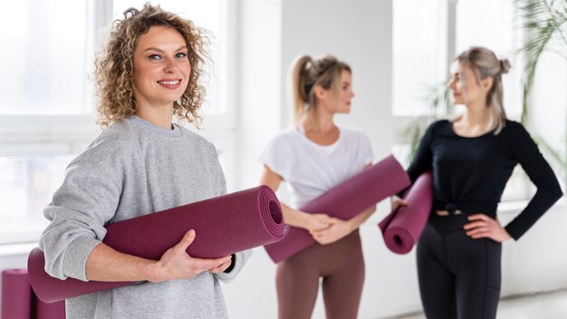 Medium shot smiley women with yoga mats