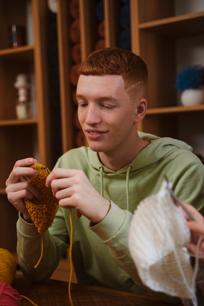 Free photo medium shot smiley young man crocheting