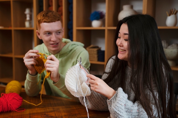 Medium shot smiley young people crocheting