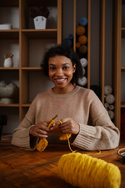 Medium shot smiley young woman crocheting