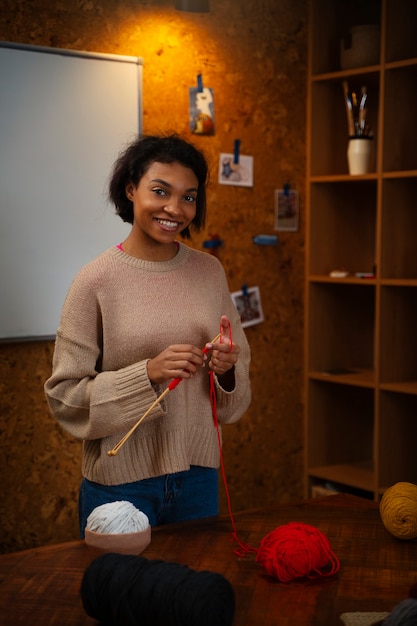 Medium shot smiley young woman knitting