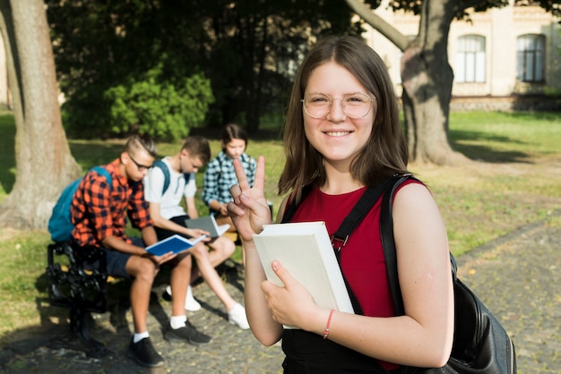 Средний снимок улыбающейся старшеклассницы с книгой в руках