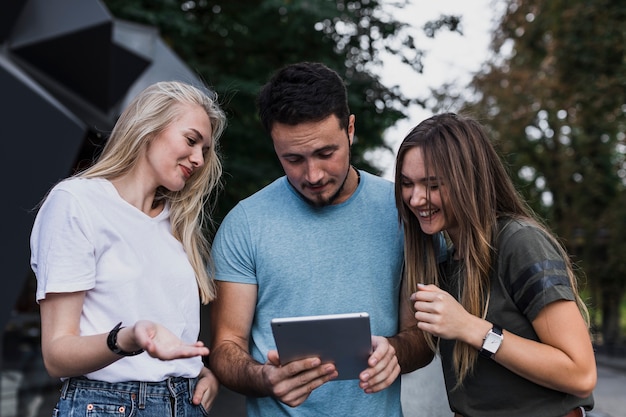 Medium-shot smiling teens looking in a tablet