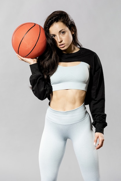 バスケットボールのボールを持つスポーティな女性のミディアムショット
