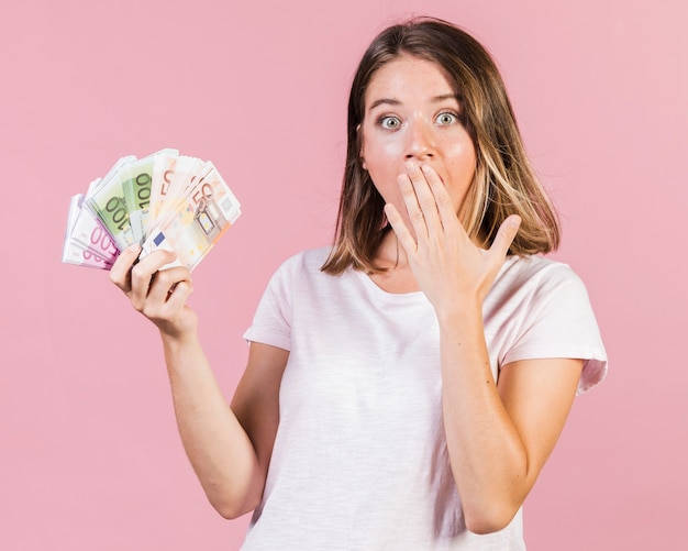 Free photo medium shot surprised girl holding money