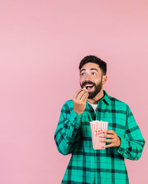 Medium shot surprised guy eating popcorn