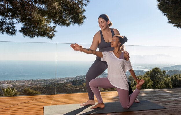 Medium shot teacher helping woman at yoga