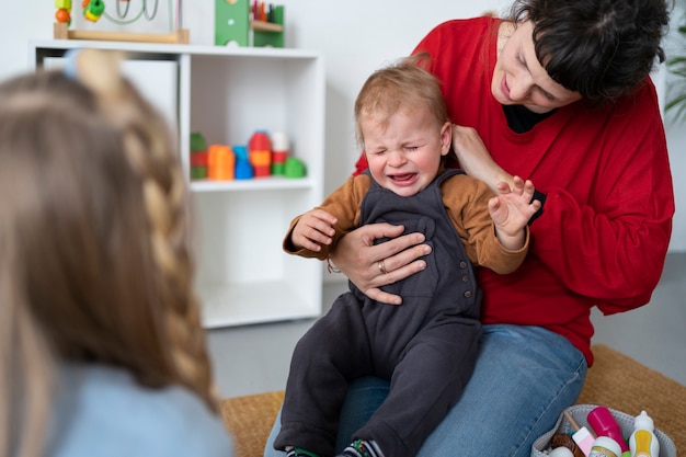 Foto gratuita insegnante di tiro medio che tiene un bambino che piange