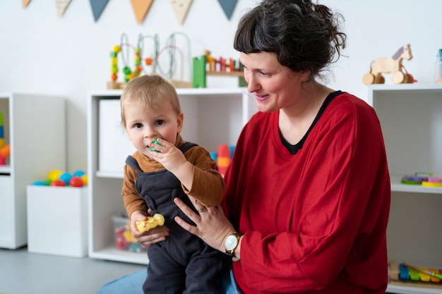 Free photo medium shot teacher holding little kid