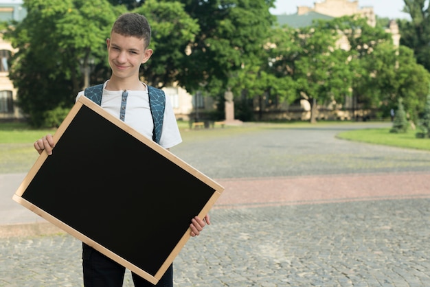 Medium shot teenage boy holding  black board