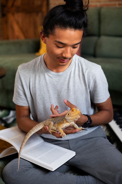 Бесплатное фото Подросток среднего роста с ящерицей дома