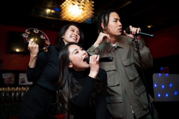 Free photo medium shot teens singing with microphones