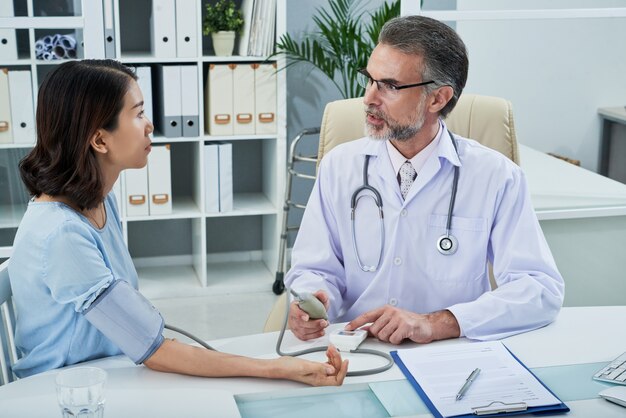 Medium shot of therapist measuring blood[ressure of the patient at the consultation