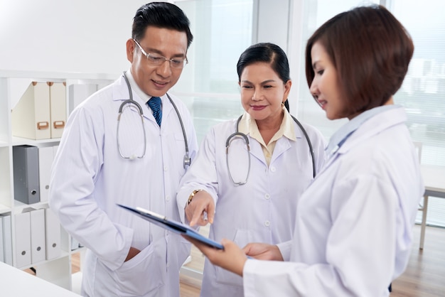 Medium shot of three doctors analyzing list of symptoms