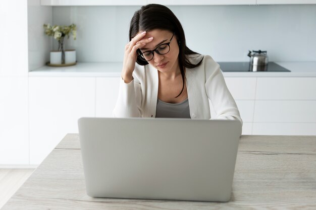 Средний снимок уставшей женщины, работающей дома с ноутбуком