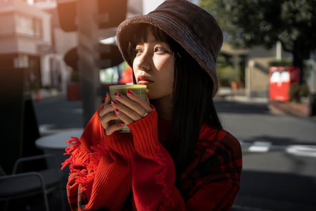 Foto gratuita bevanda alla moda della tenuta della donna del colpo medio