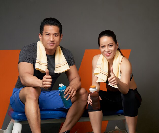 Medium shot of two coaches showing thumbs up to the camera to support and motivate to do sports