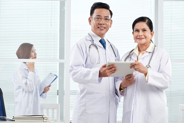 Medium shot of two doctors standing in the medical office discussing clinical case