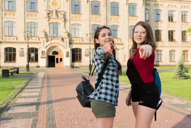 カメラを指している2つの高校生の女の子のミディアムショット